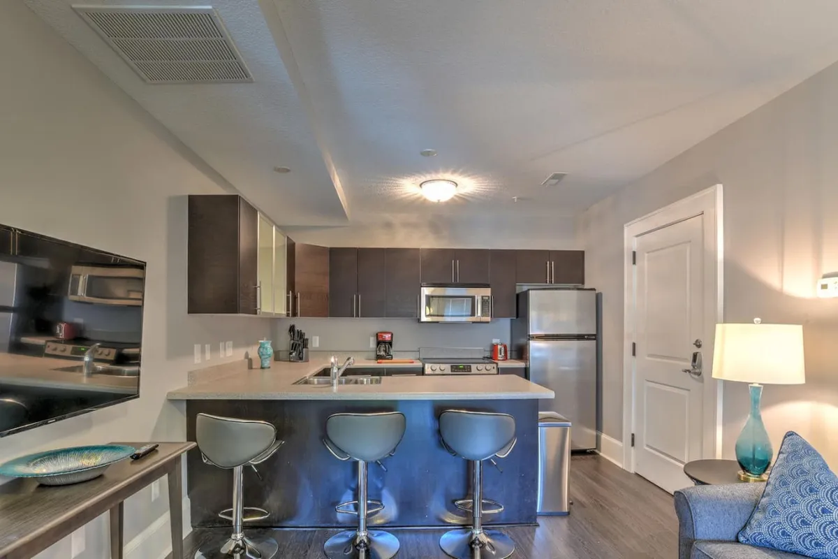 A contemporary kitchen featuring a spacious island, sleek stainless steel appliances, and bar stools lined up for casual dining. The setup is open and inviting, ideal for both cooking and socializing, with updated finishes that contrast nicely against any preserved historic elements.